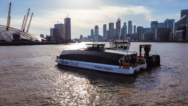 The UK's first fully electric zero-emissions ferry on the Thames with buildings behind.